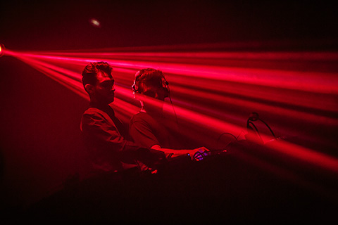 Adriatique DJing basked in red strobe light