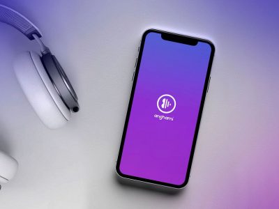 Mobile phone displaying Anghami placed next to headphones