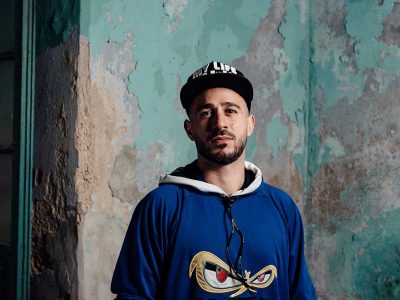 Arab hip-hop artists Dave Kirreh against wall of flaking paint