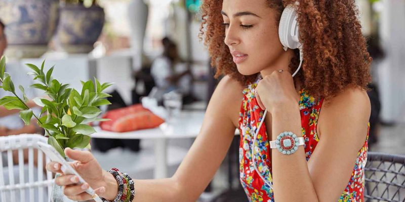 Girl with afro hair listening to music on phone with headphones