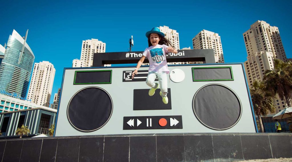 DJ Michelle jumping in front of large fake ghetto blaster