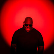 DJ Carl Cox smiling against red sunset effect background