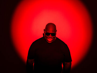 DJ Carl Cox smiling against red sunset effect background