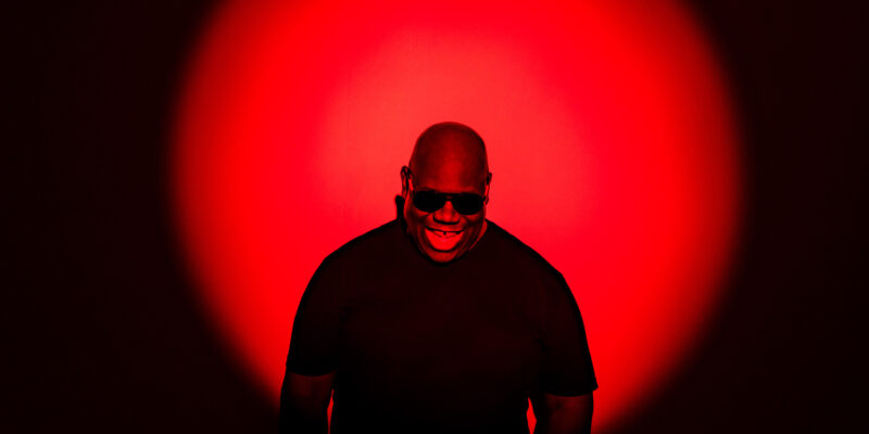 DJ Carl Cox smiling against red sunset effect background